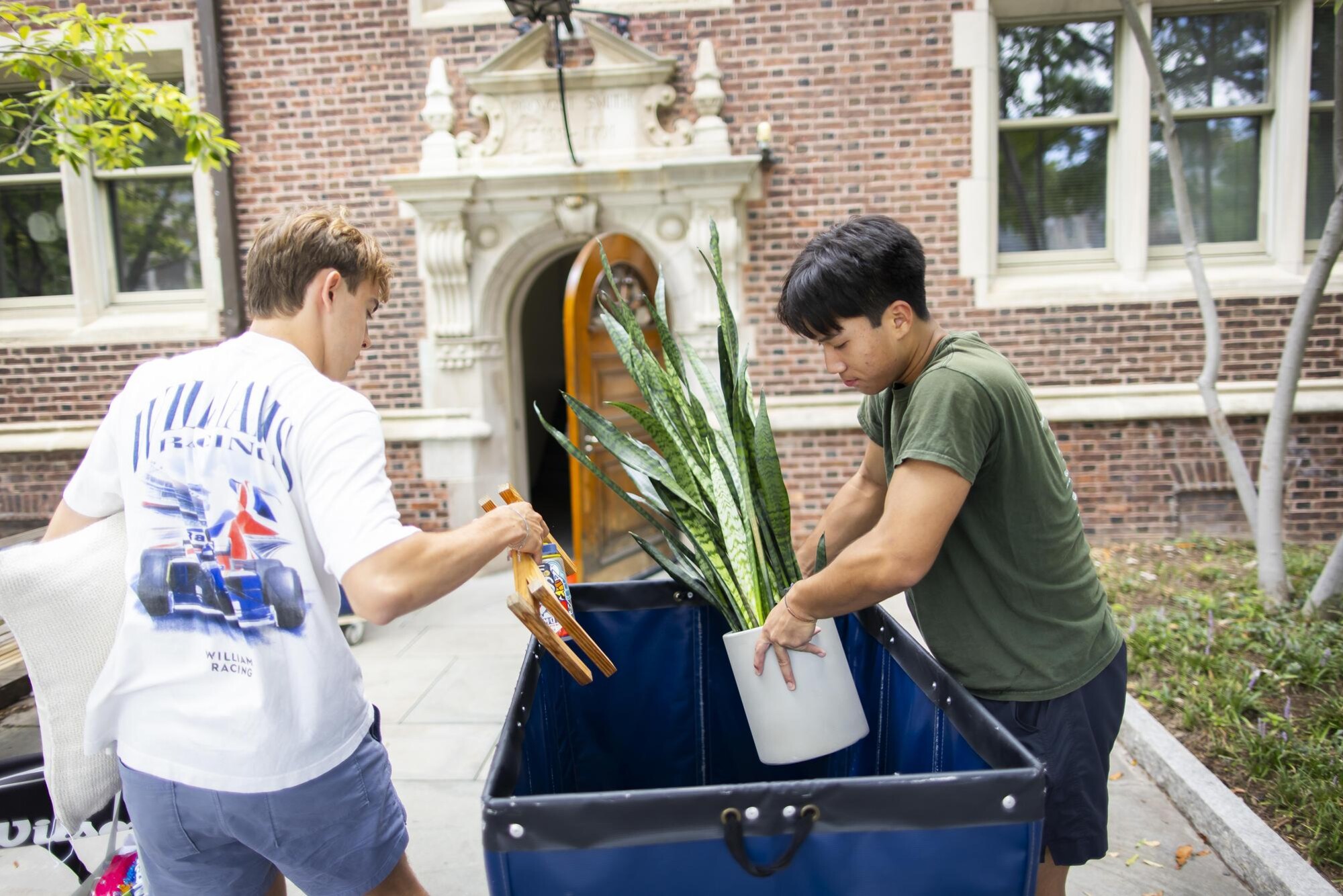 Two Penn students unload items from a Move-In cart outside a dorm on Move-In day.