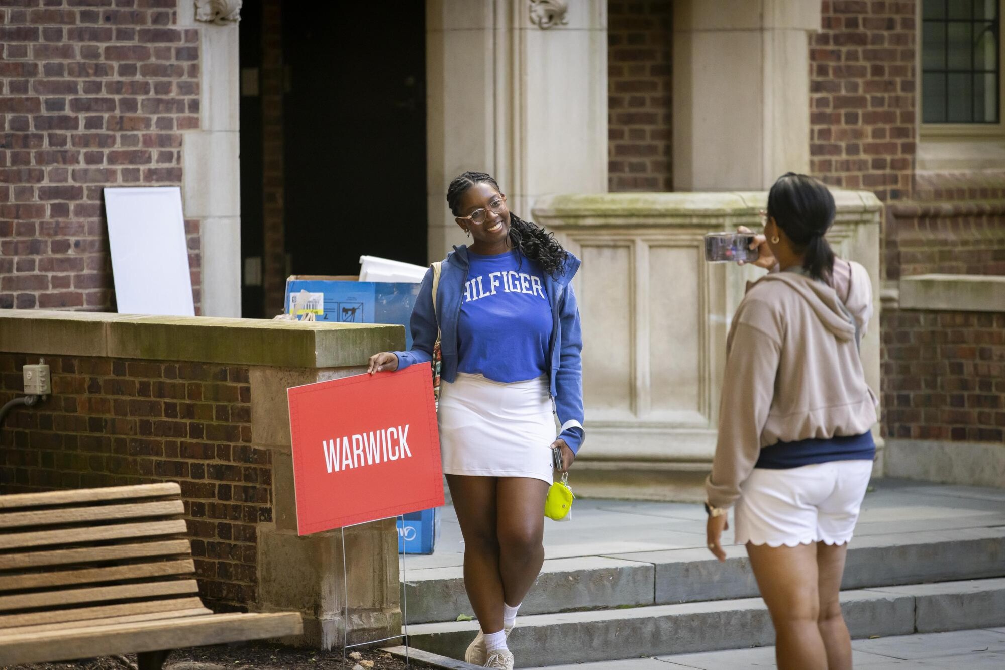 A student poses for a photo by a Warwick sign outside a Penn dorm on Move-In day.