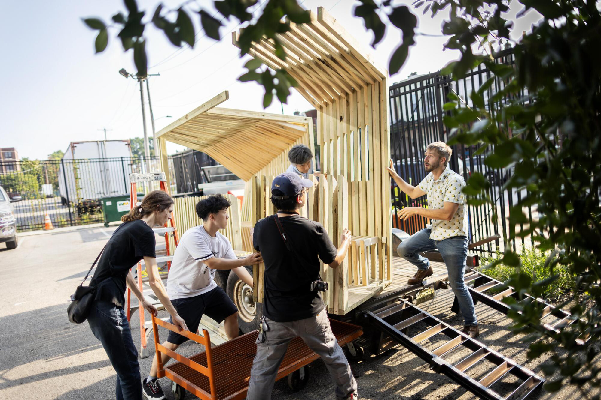 Five people work on installing a pre-built cooling shelter on-site.