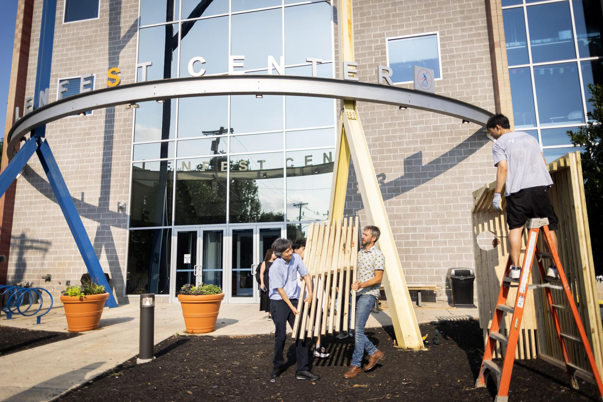 Outside the Lenfest Center, Mark Yim, Eric Teitelbaum, and others install a wooden cooling shelter prototype.