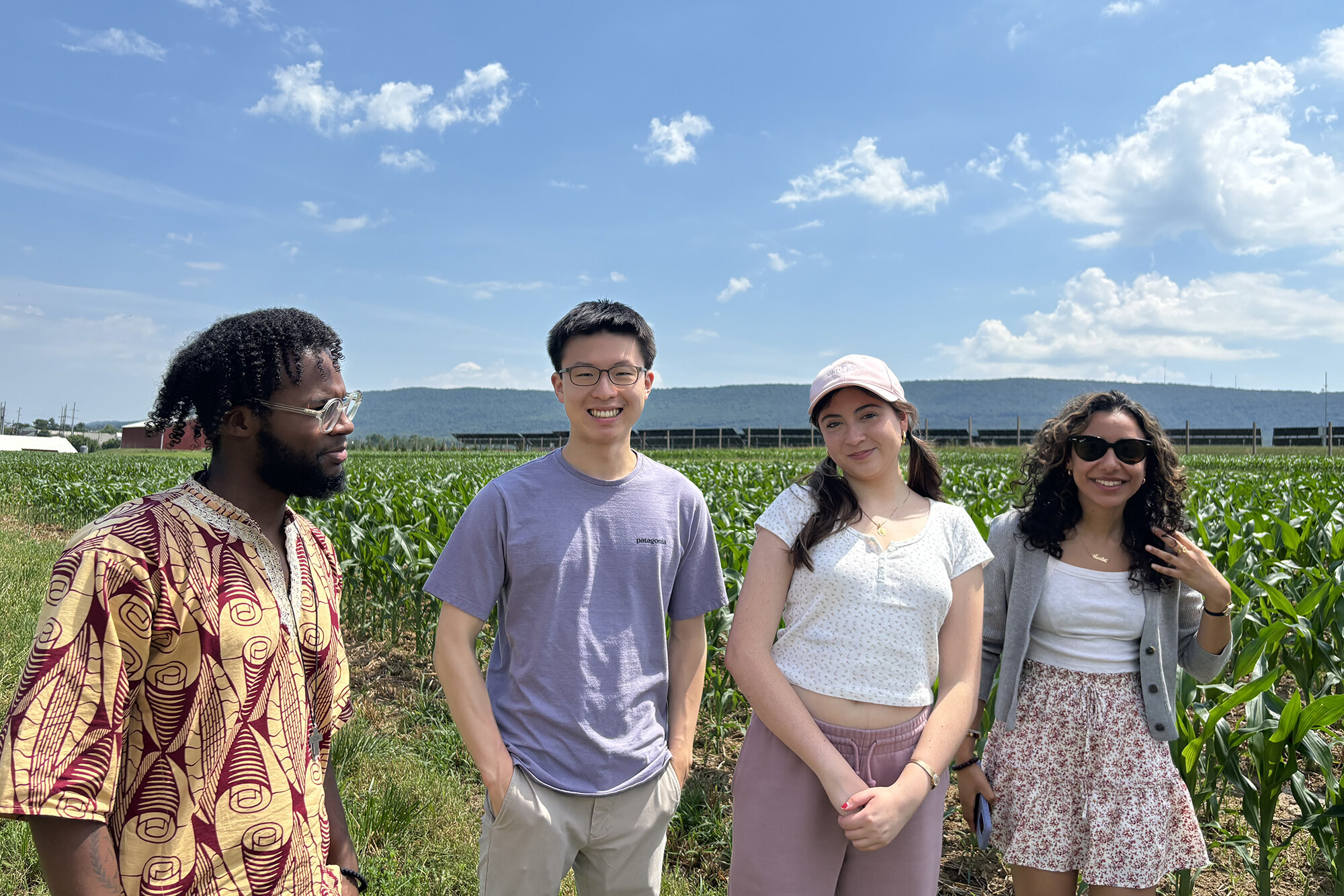 Four members of Penn’s Political Empathy Lab group in a corn field with solar panels in the background.