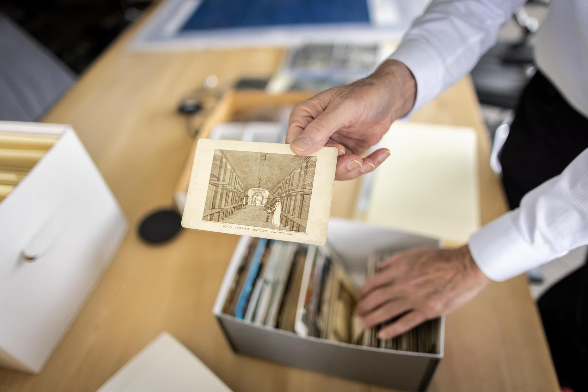 A library archivist holds a historic photo of a public market.