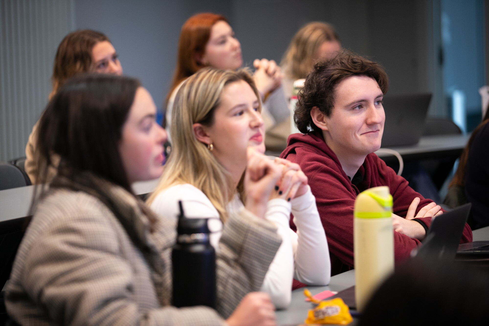 students in class listen to speaker at podium