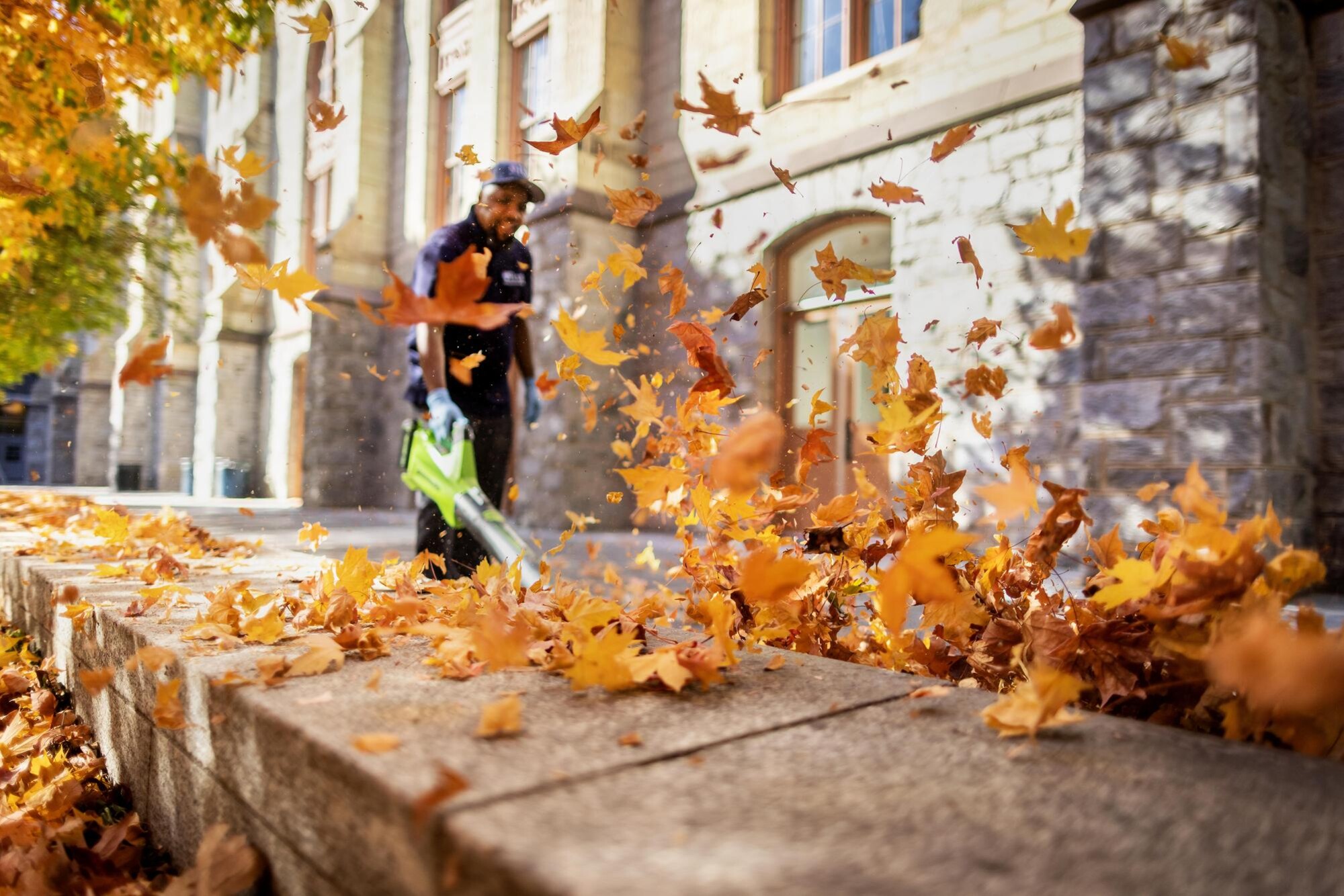 A person with a leaf blower outside College Hall.