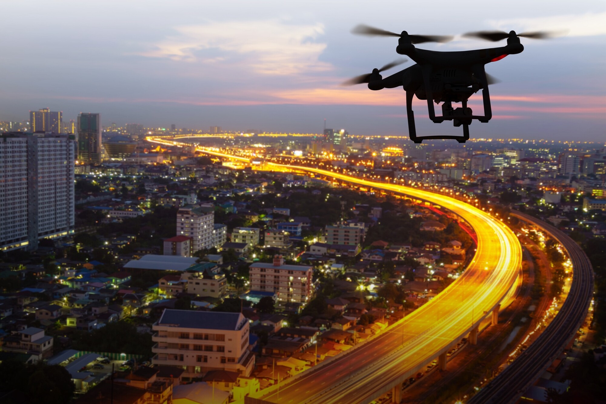 Picture of a drone flying lit nighttime cityscape