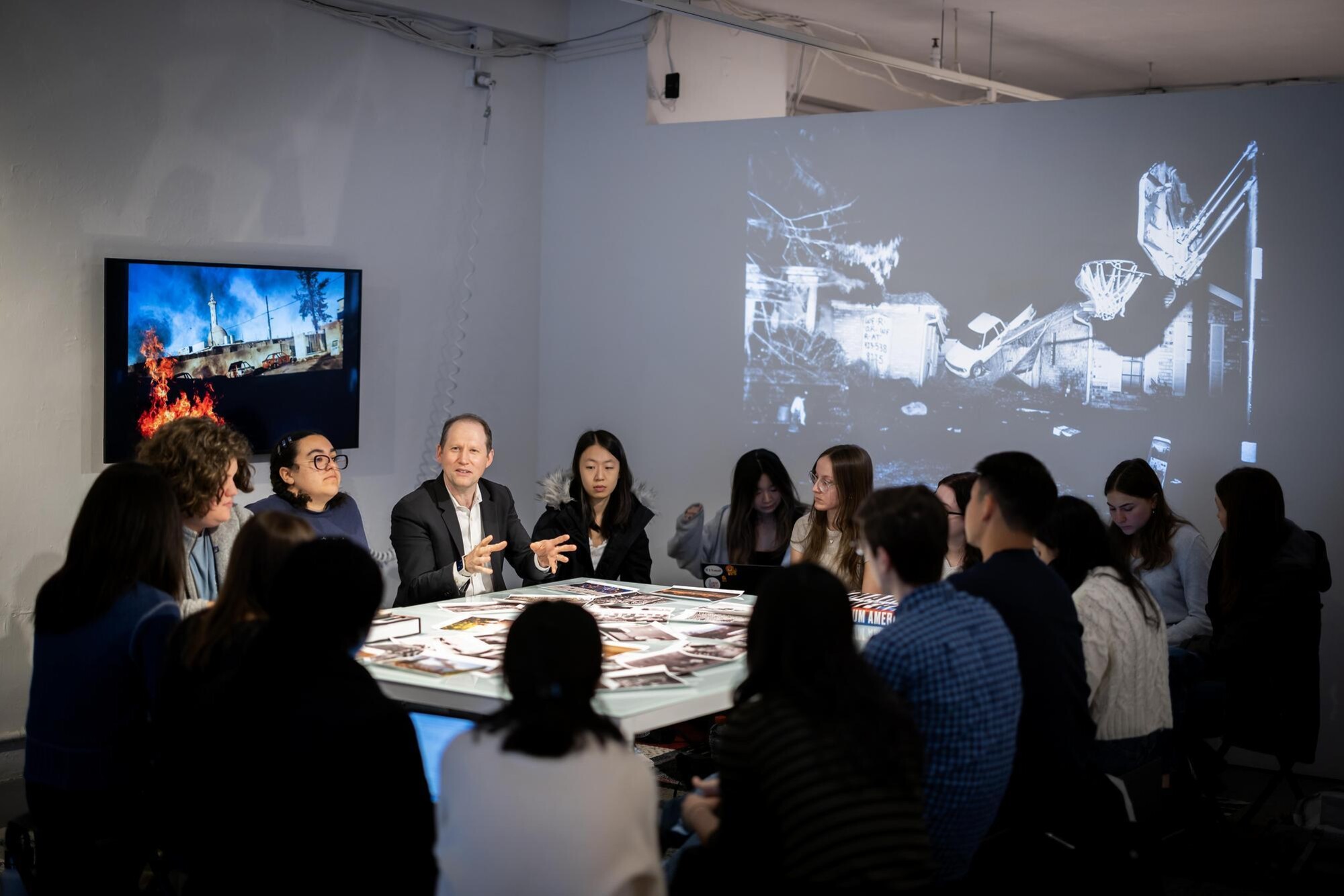 Aaron Levy and students gathered around a table filled with images. 