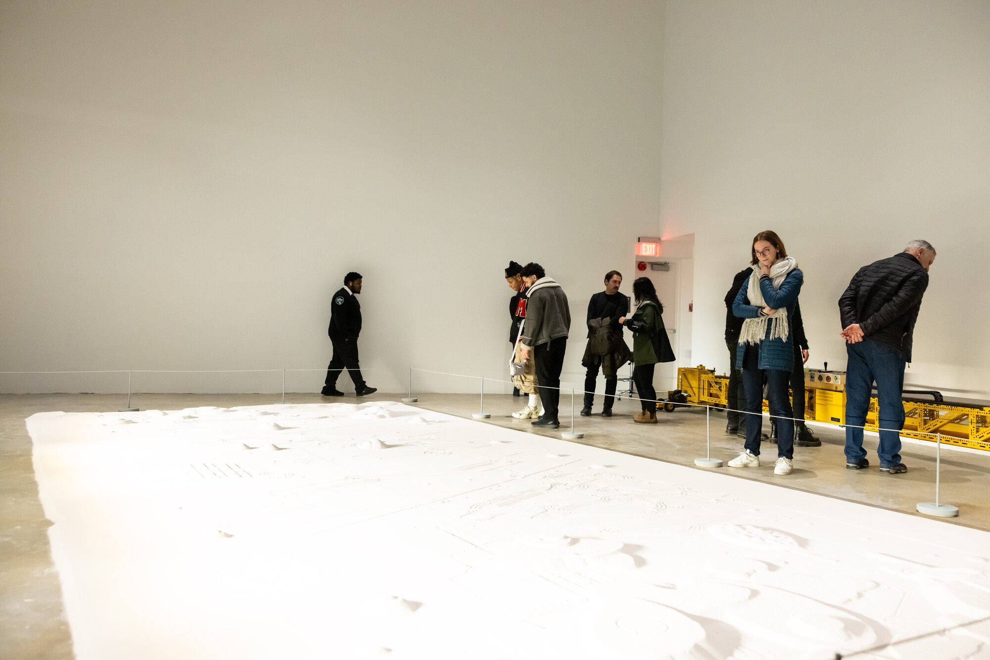 sand sculpture filling the cement floor of a room with people looking at it 