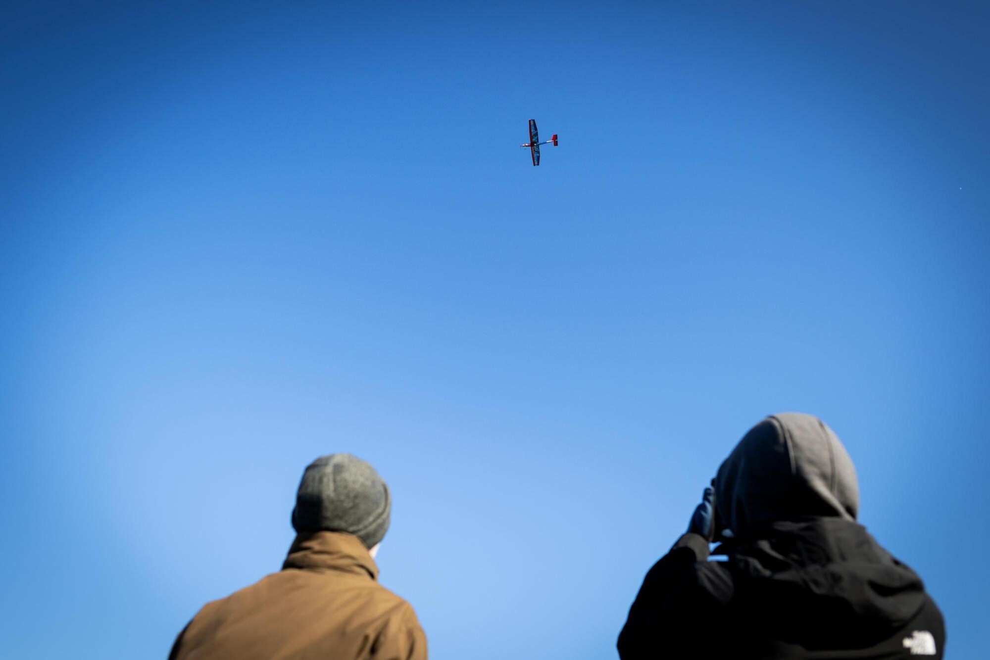 Penn’s drone aircraft aloft in the air with two spectators looking.