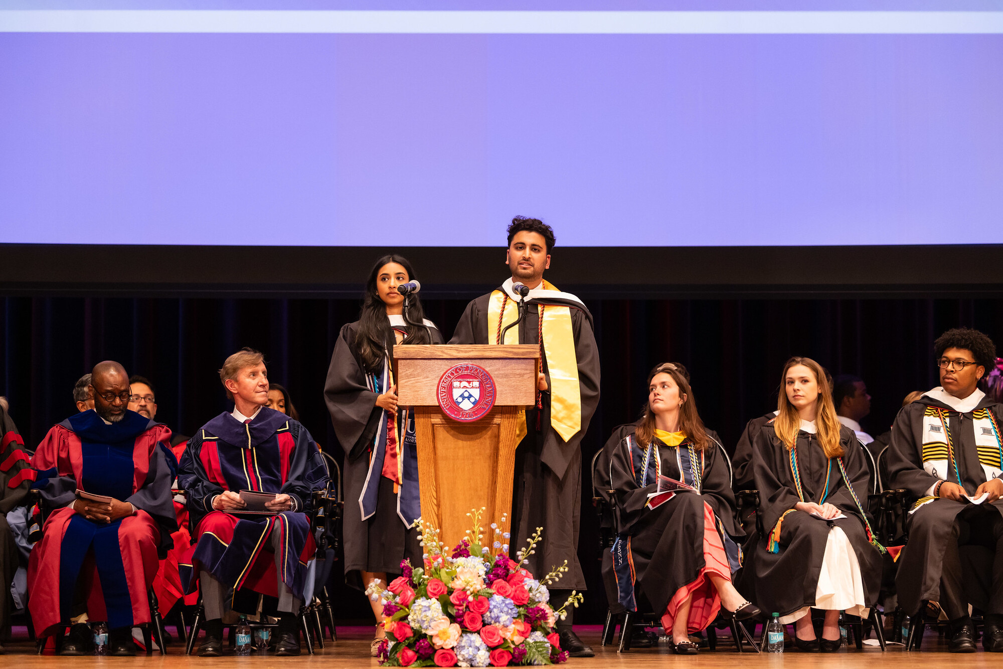 Two students speaking at a the podium at Penn’s Baccalaureate ceremony.