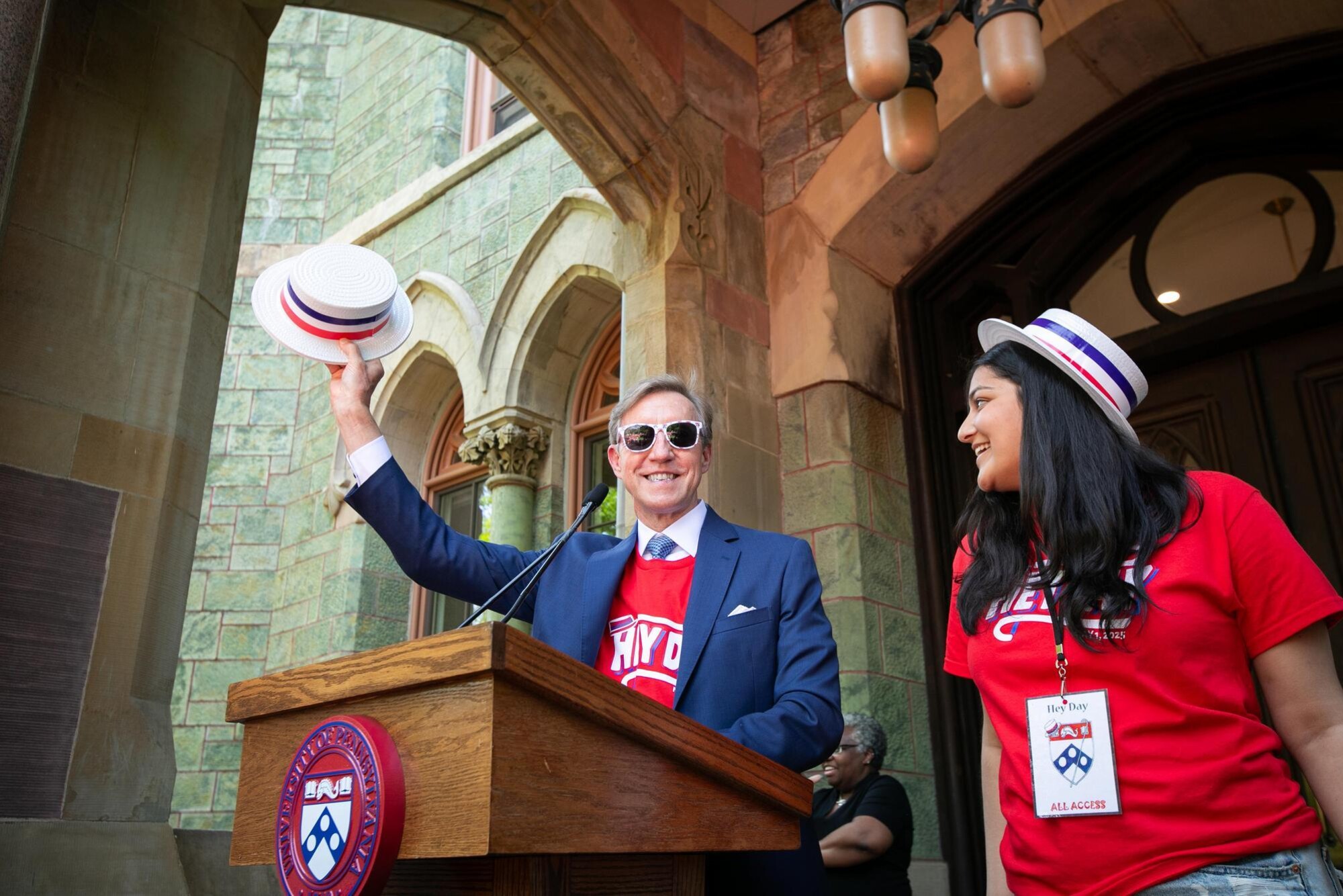 Penn president J. Larry Jameson waving his hat at the podium on the steps of College Hall during Hey Day.