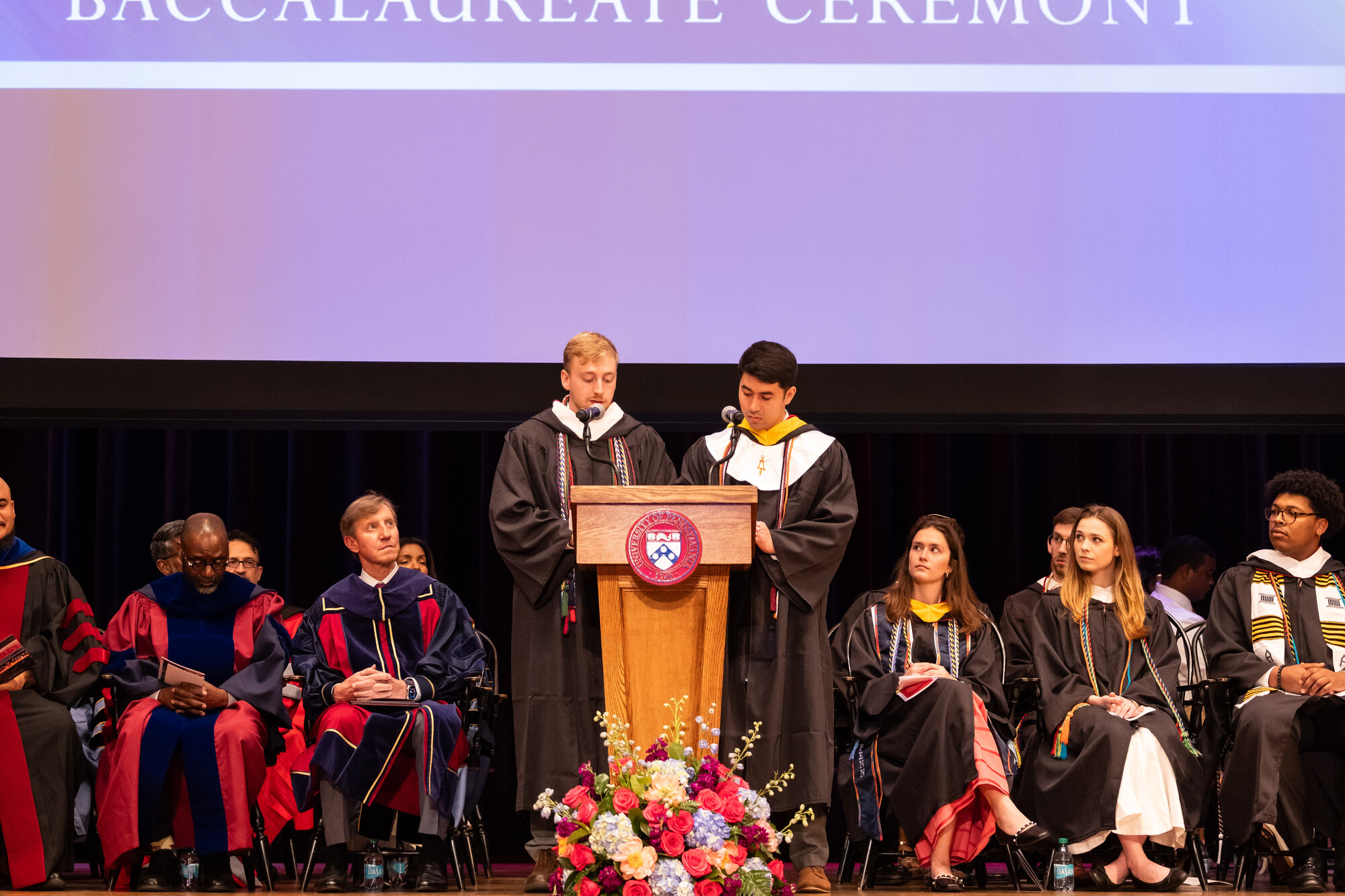 Two students speaking at the podium during Penn’s Baccalaureate celebration.