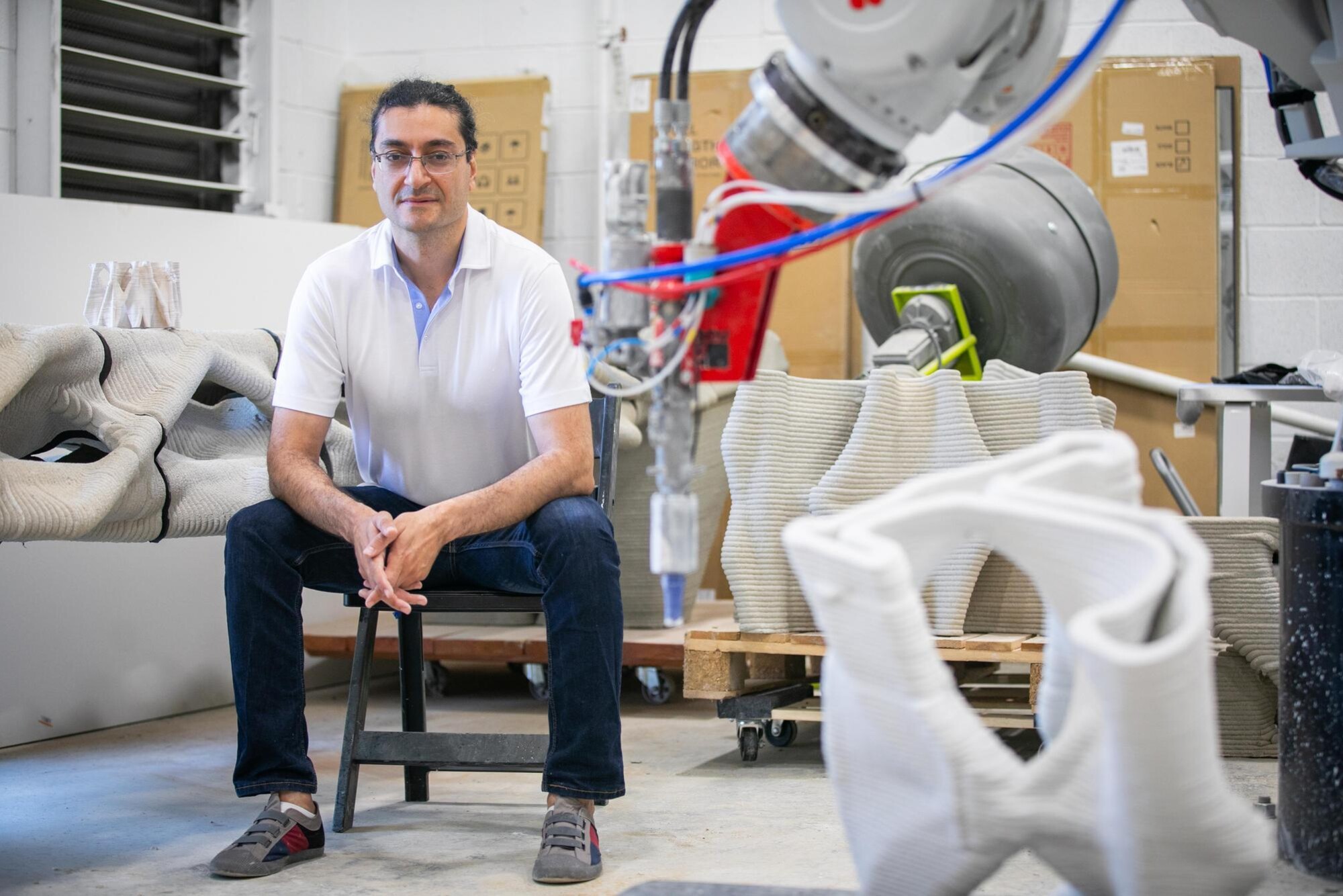Masoud Akbarzadeh seated in the lab surrounded by fabricated materials.