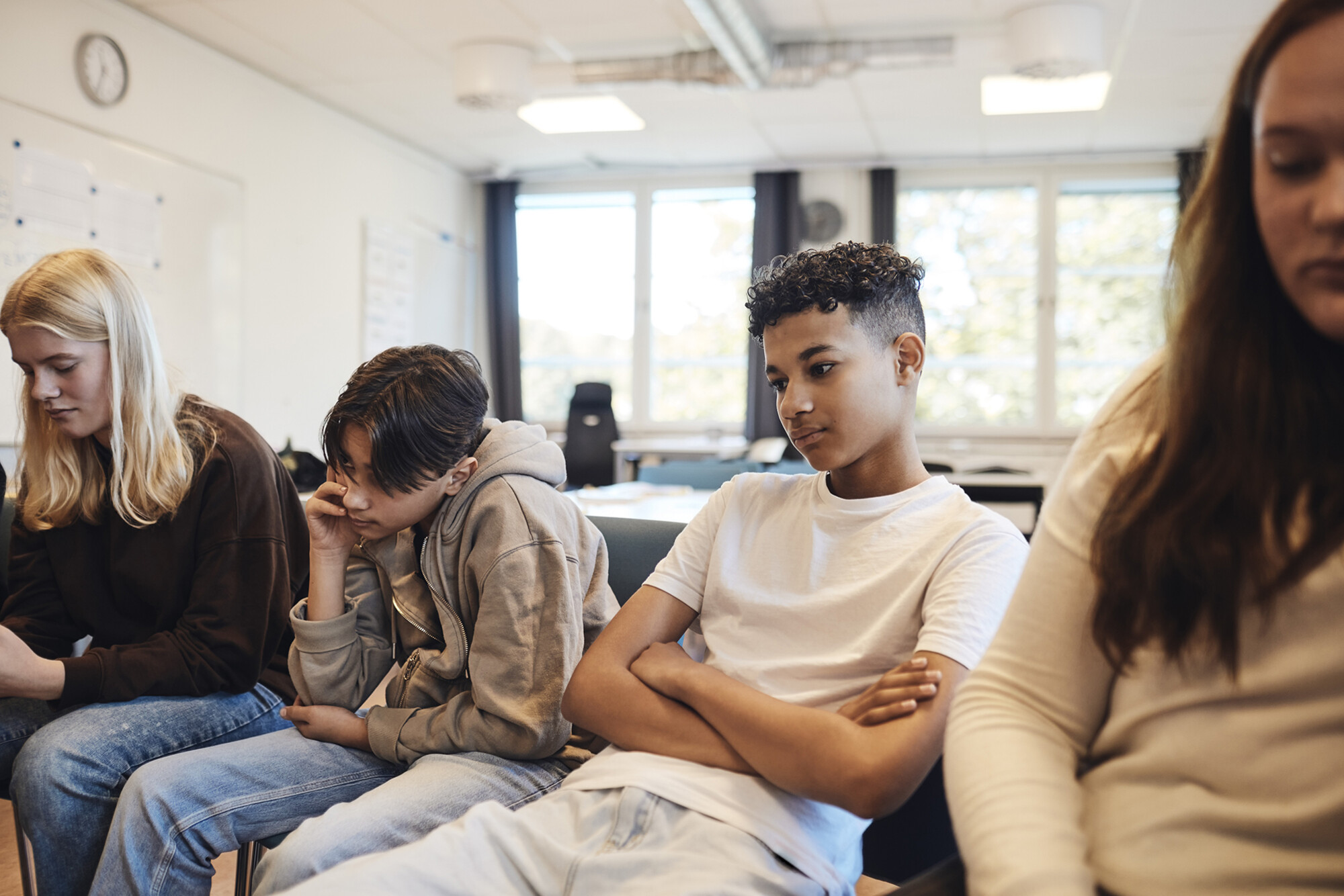 Four teens looking unhappy on a couch.