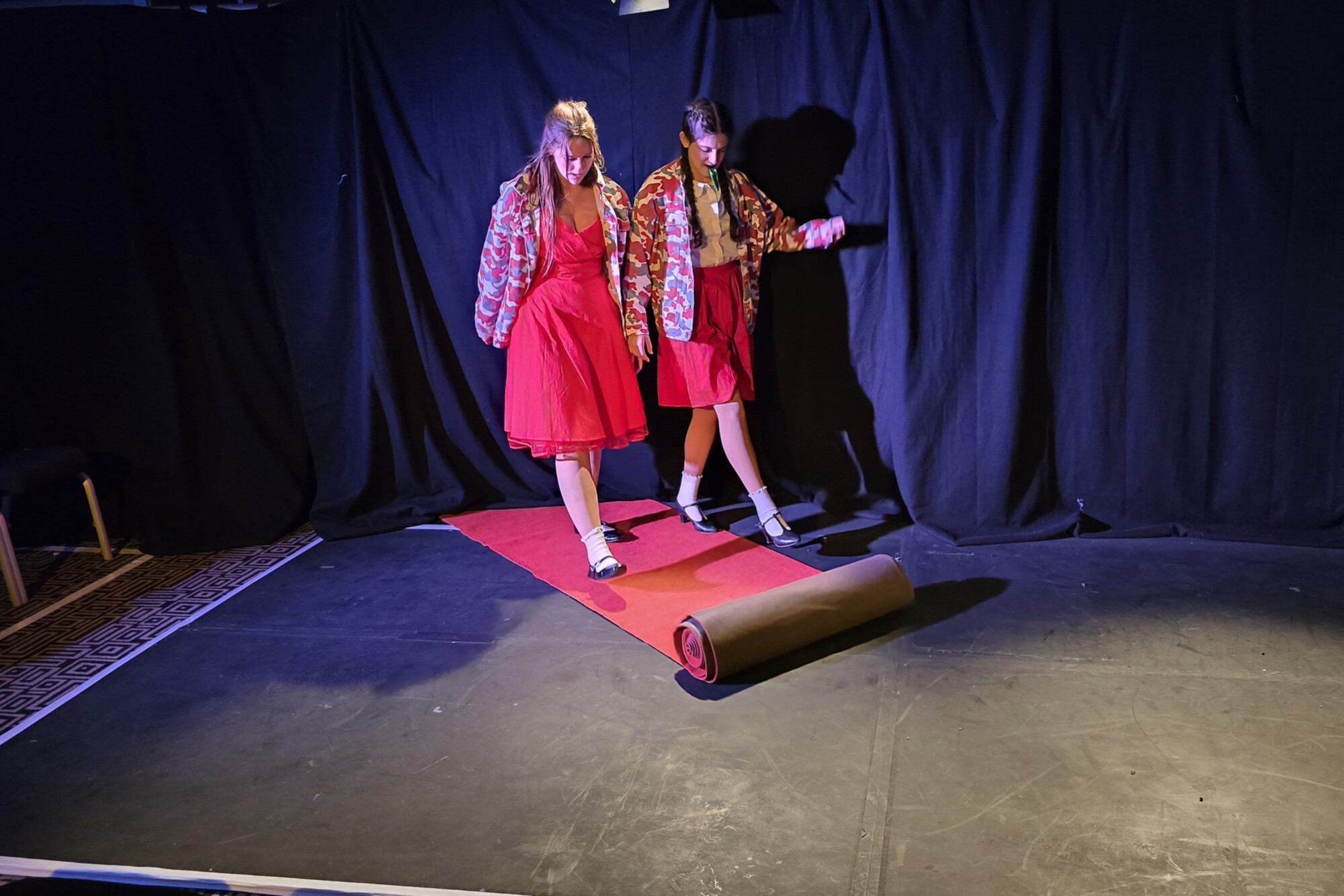 Pandora Schoen and Anya Rothman walking down an unrolling red carpet while performing in Edinburgh.