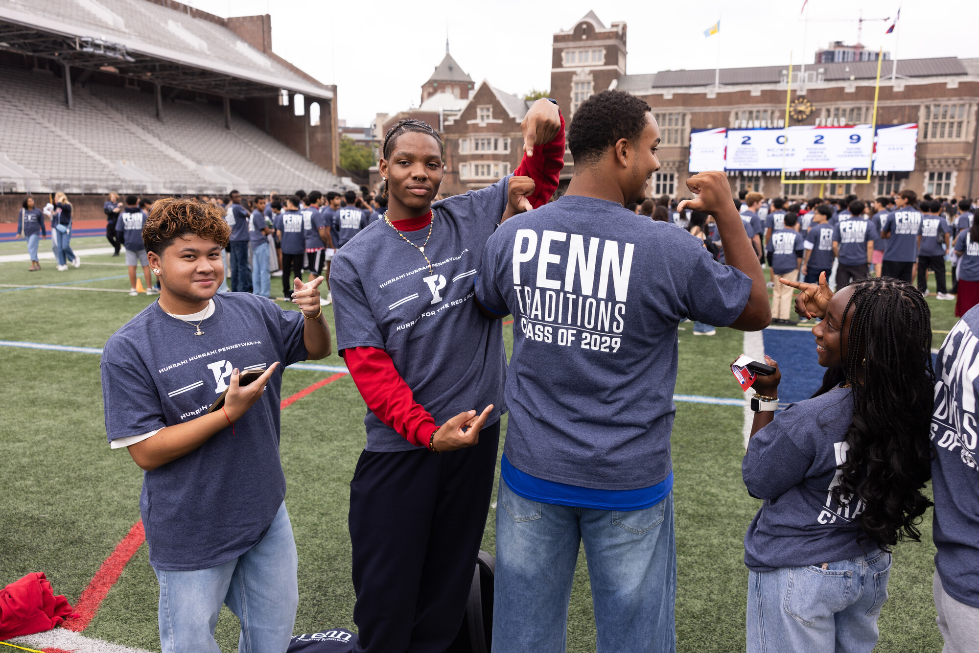 Four students on Franklin Field wearing Penn Traditions Class of 2029 T-shirts.