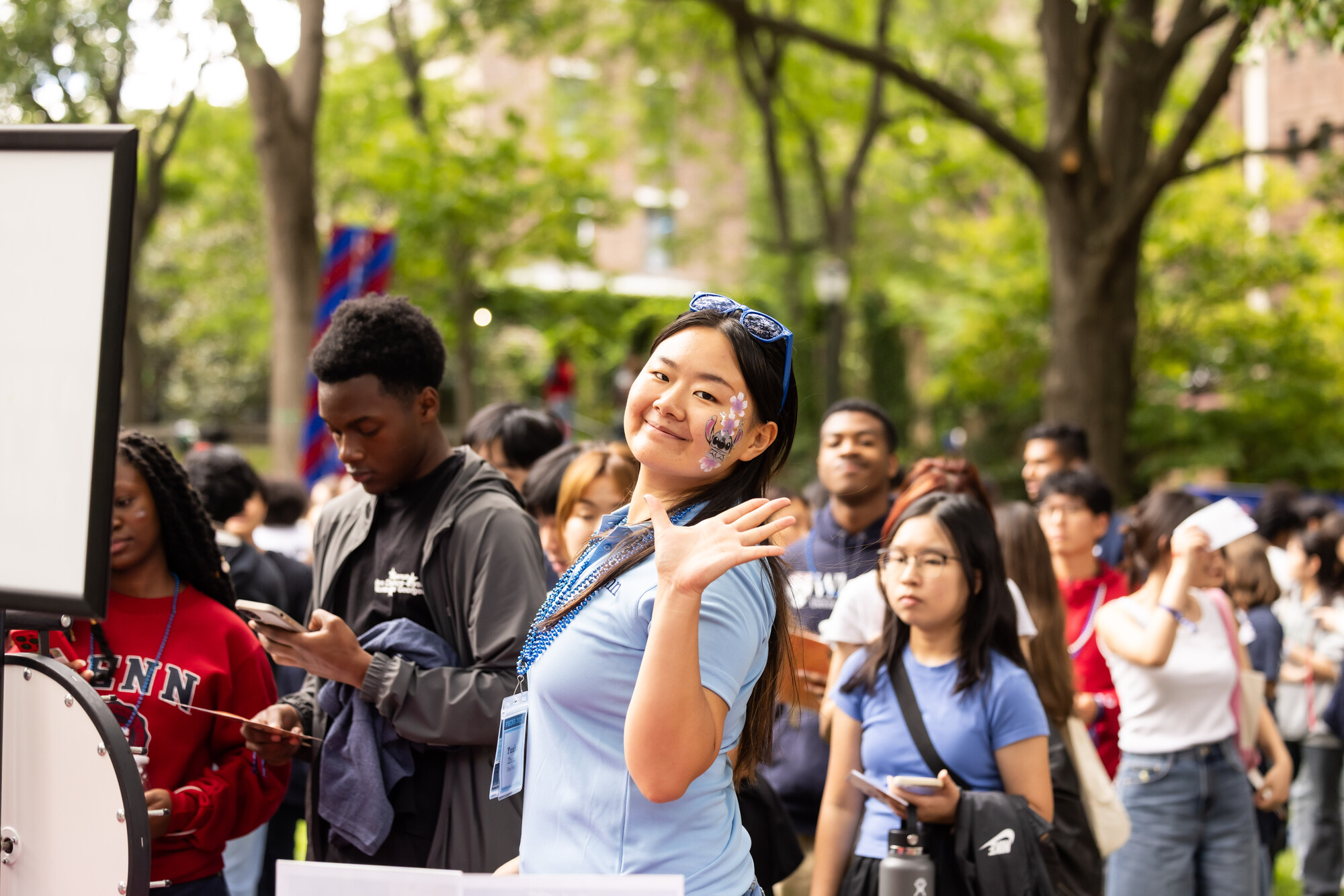 A Penn student with face paint waves at the camera.