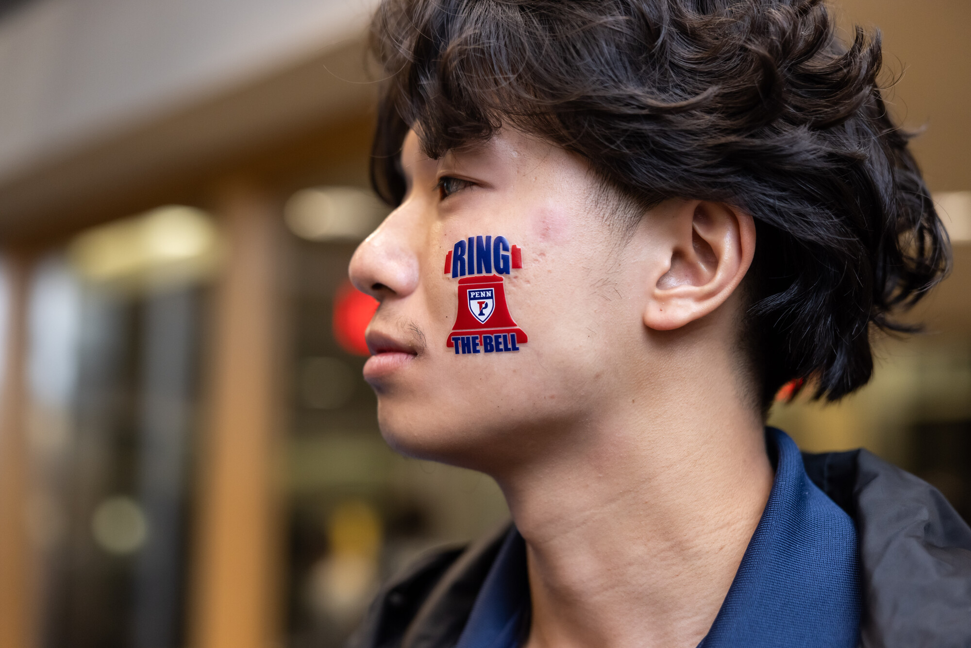A student with face paint on their cheek that reads Ring the Bell.