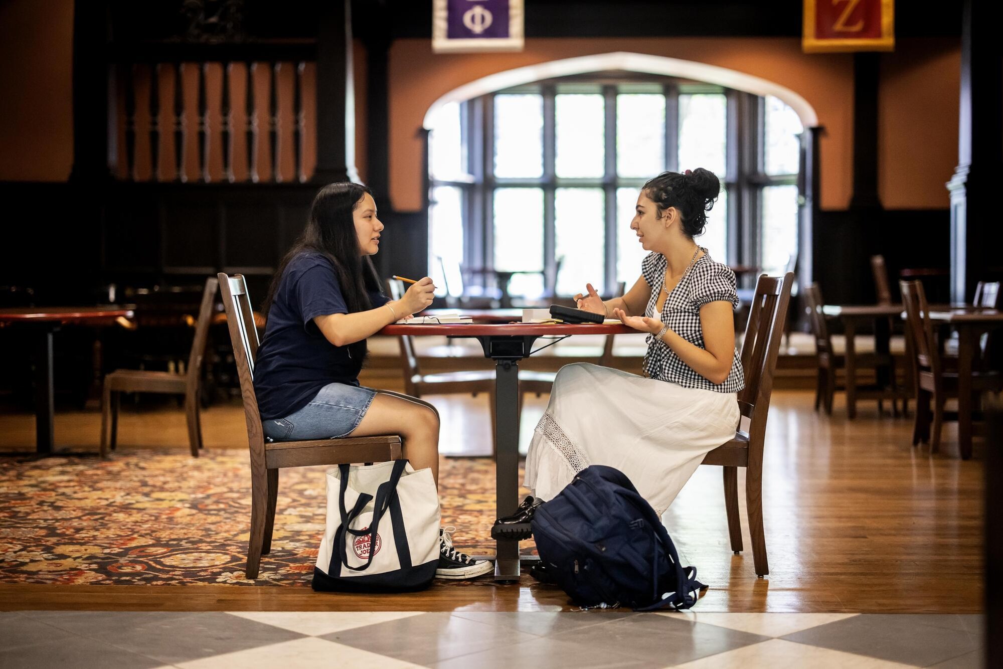Veronica Baladi and Wendy Hernandez Higarede talk at a table in Houston Hall.