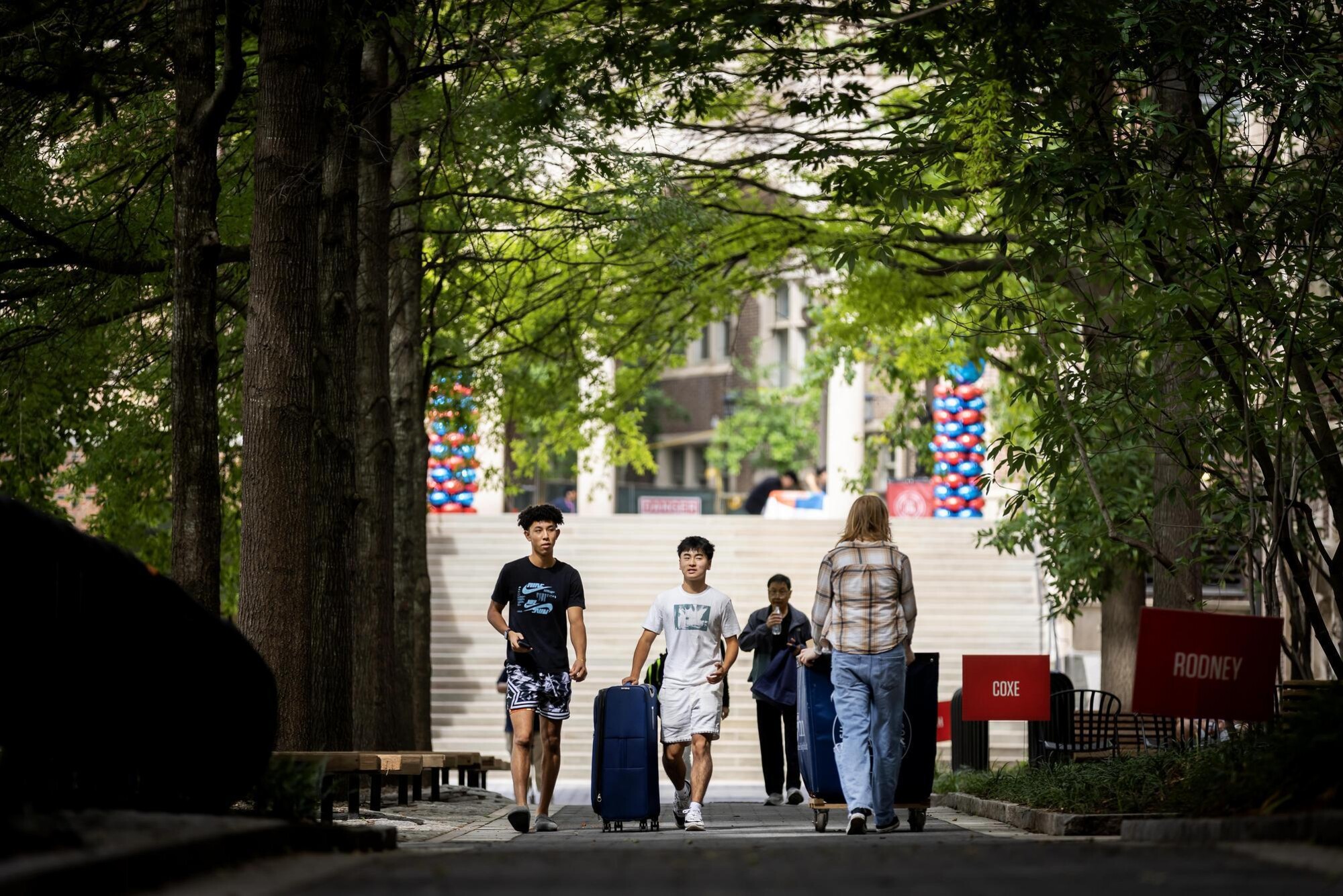 People walking along a Penn walkway with suitcases and Move-In carts during Move-In.