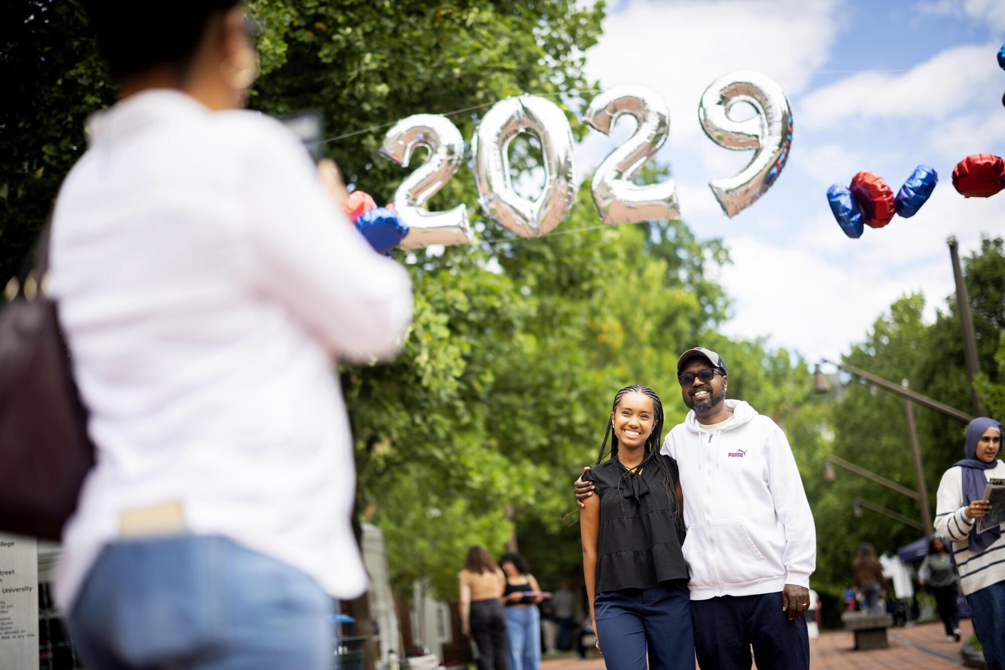 A Penn student and their parent having a photo taken under a 2029 balloon arch.