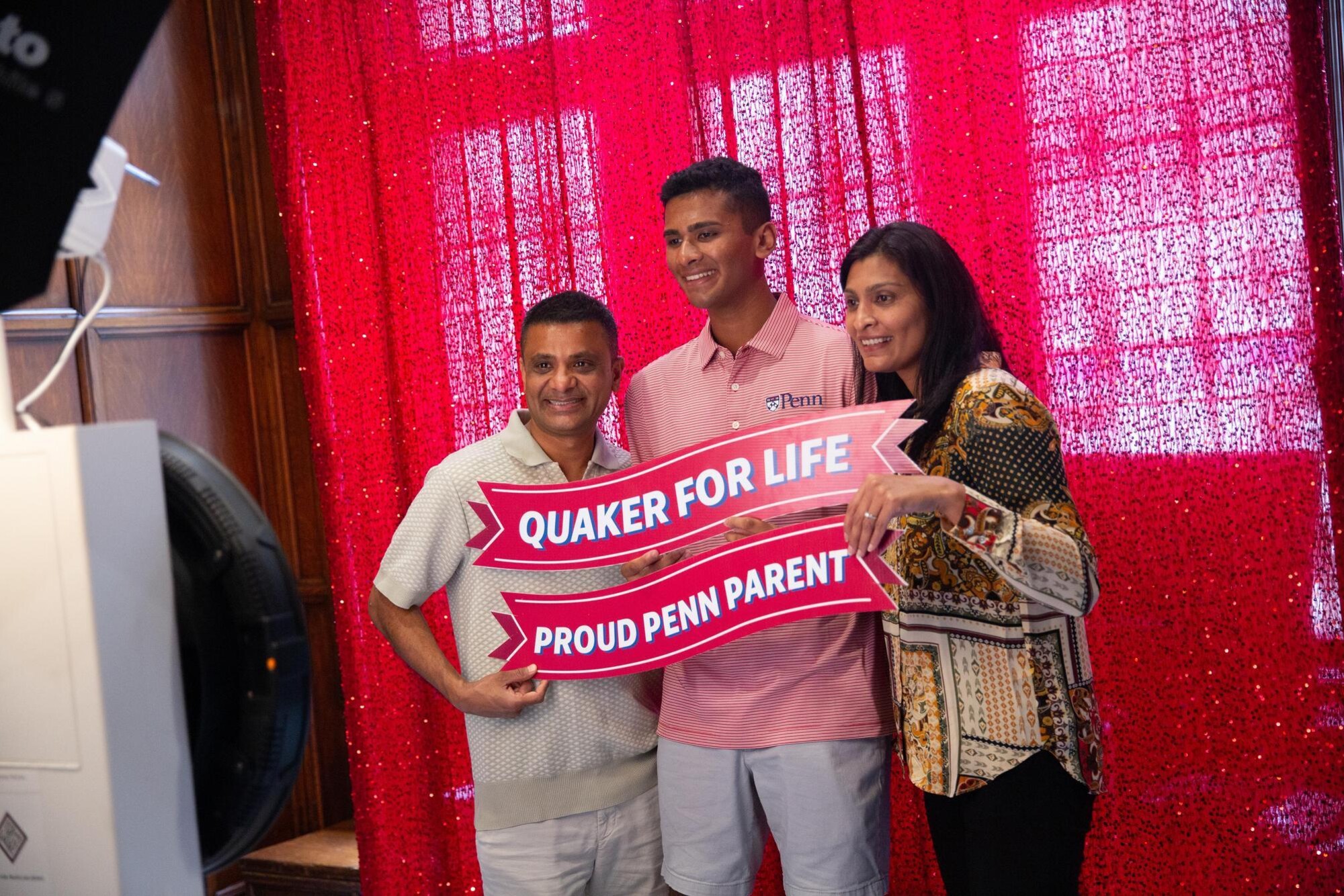 A student and their parents pose for a photo holding a banner that reads QUAKER FOR LIFE PROUD PENN PARENT
