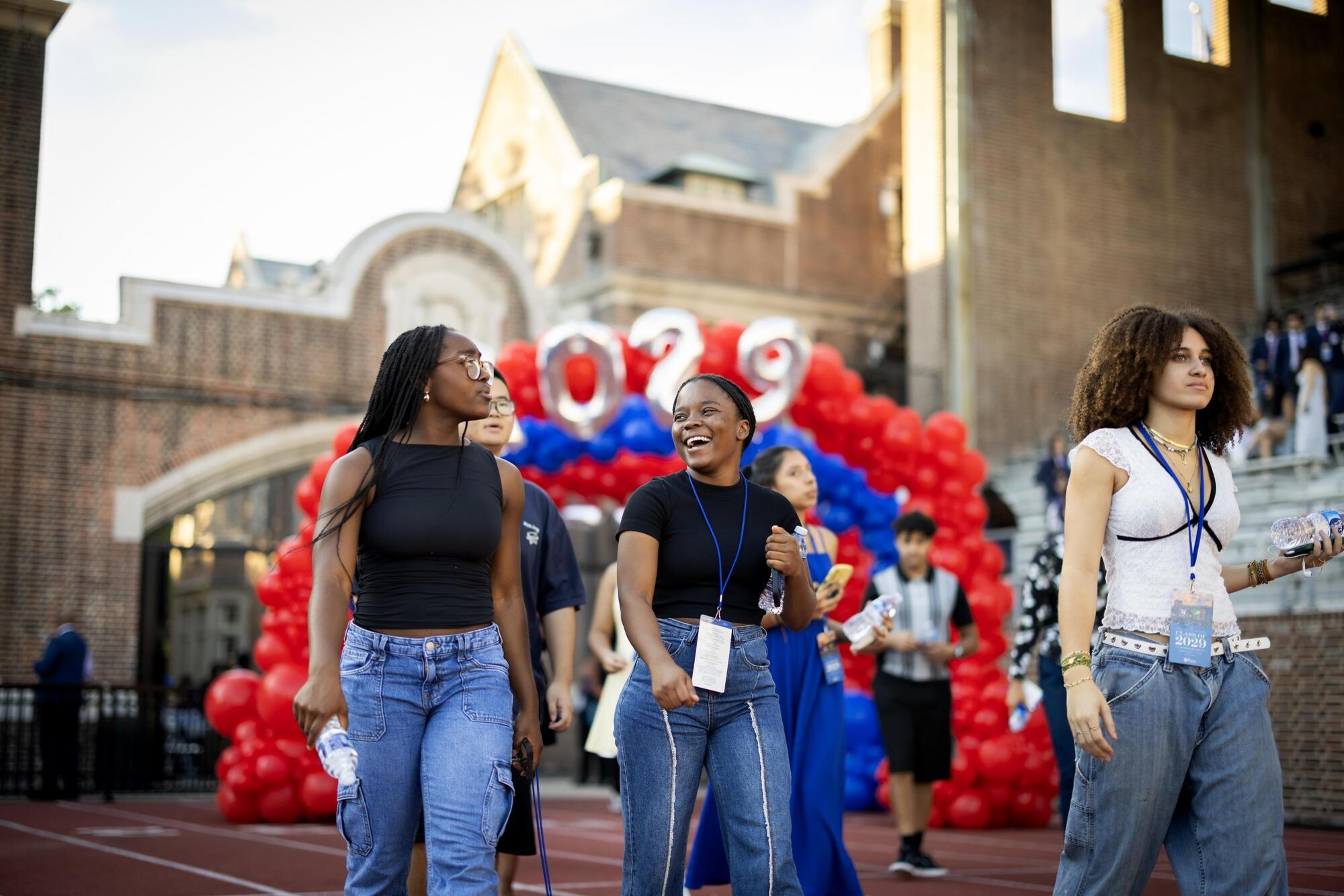 Three students walking onto Franklin Field past a balloon arch at Penn’s Convocation.