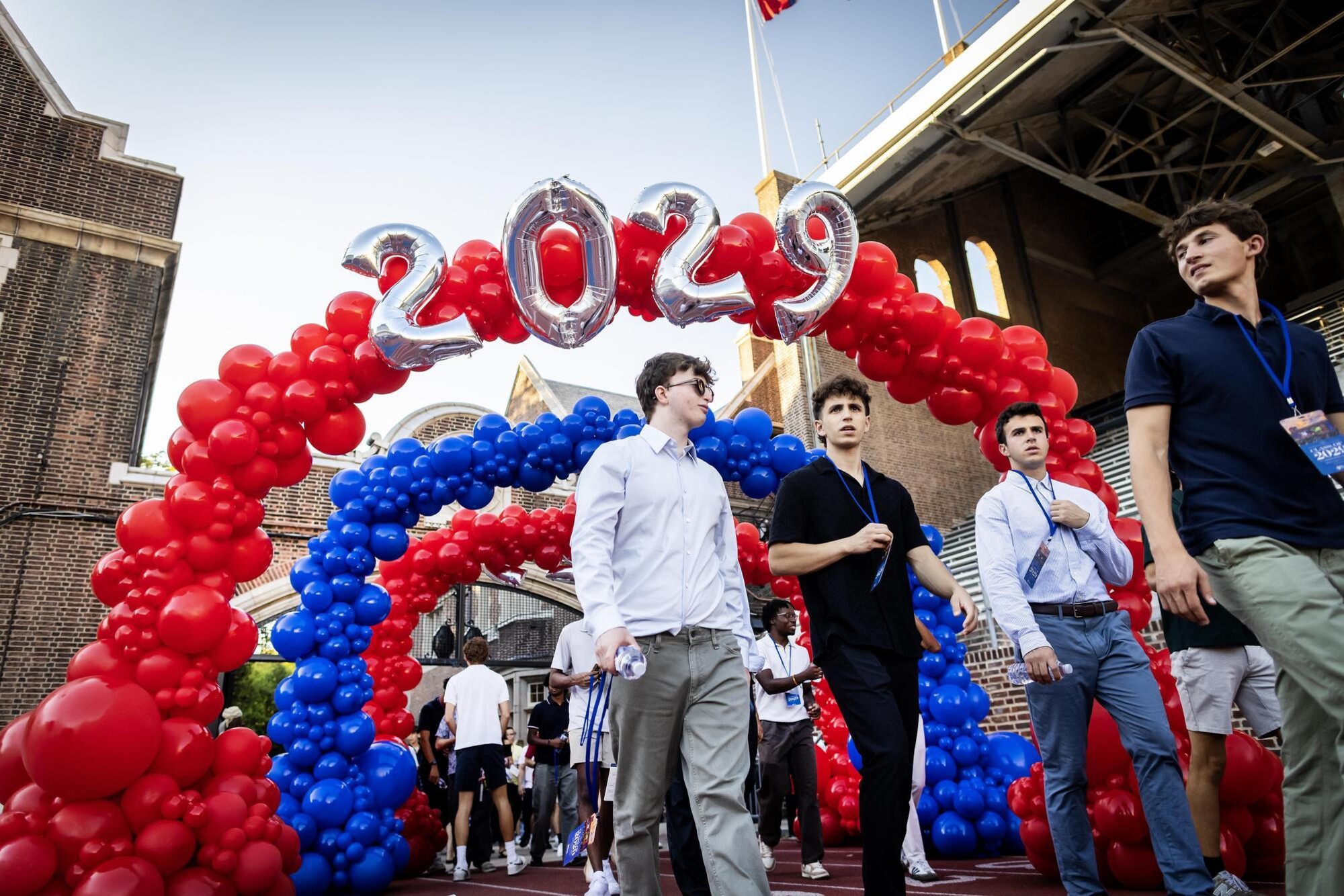 Four students walking through a balloon arch onto Franklin Field for Penn’s Convocation.