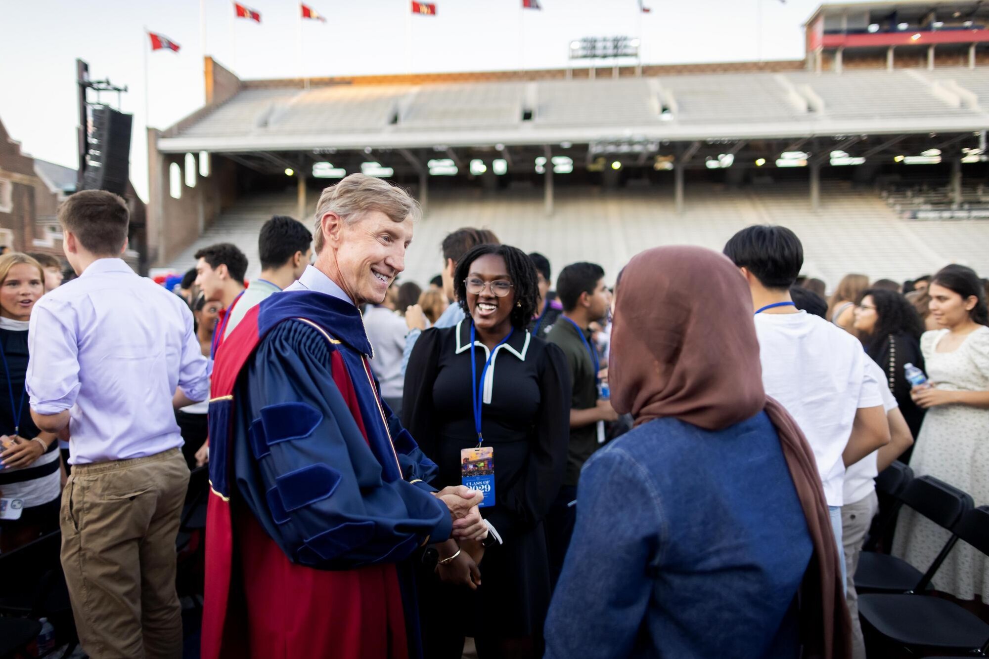 Penn President J. Larry Jameson speaks with two students on Franklin Field at Penn’s convocation.