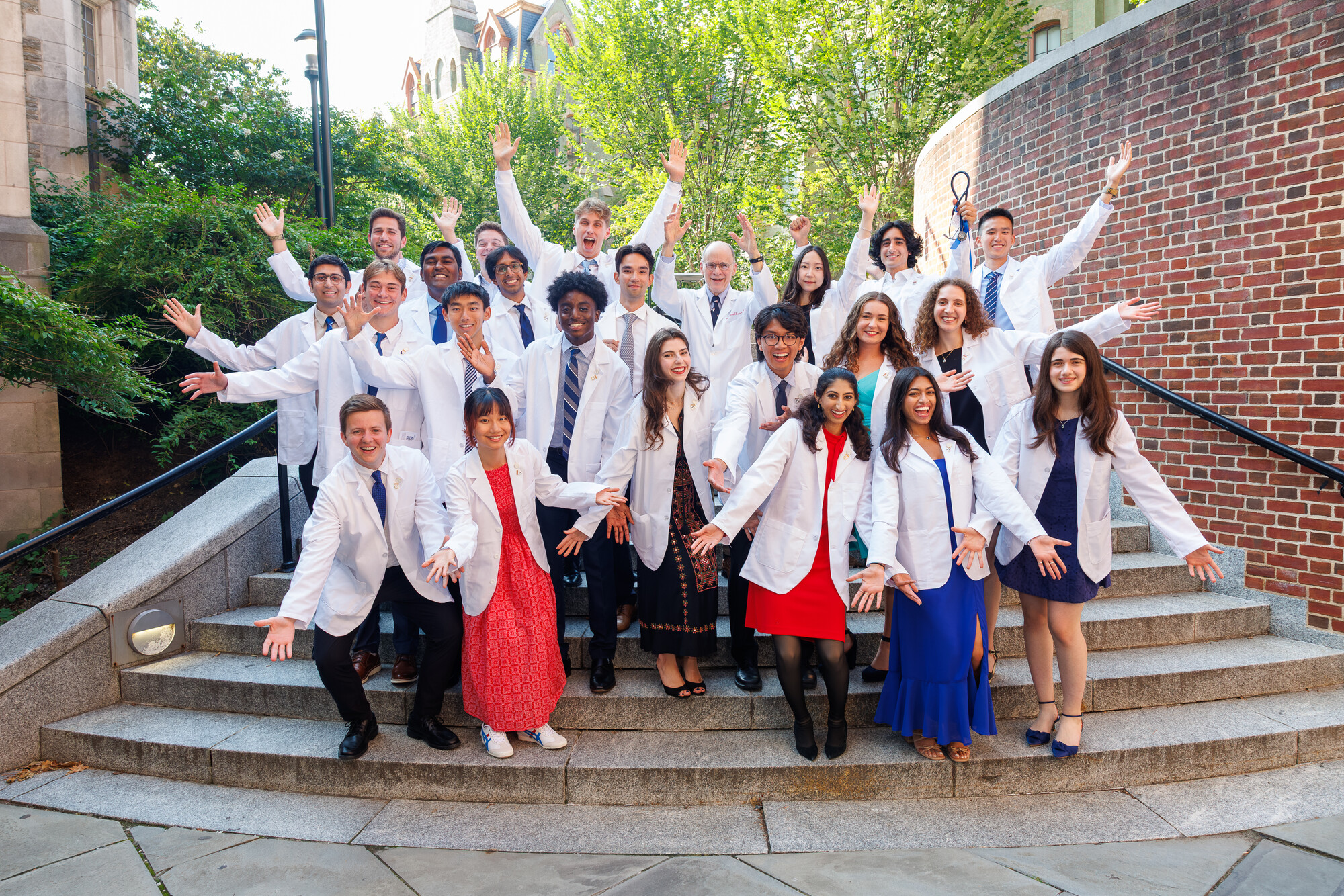 Penn med students in white coats on outdoor steps after Penn’s White Coat ceremony.