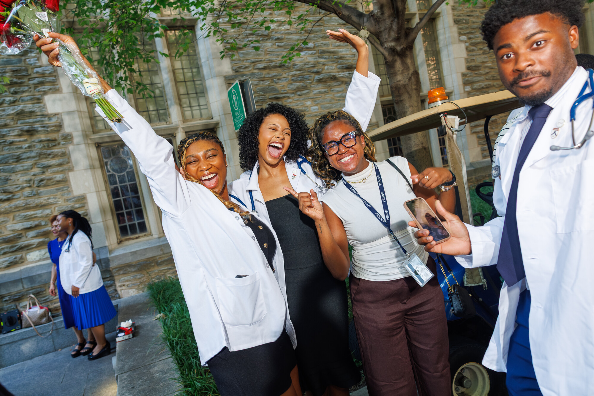 Four students celebrating in white coats after Penn’s white coat ceremony.