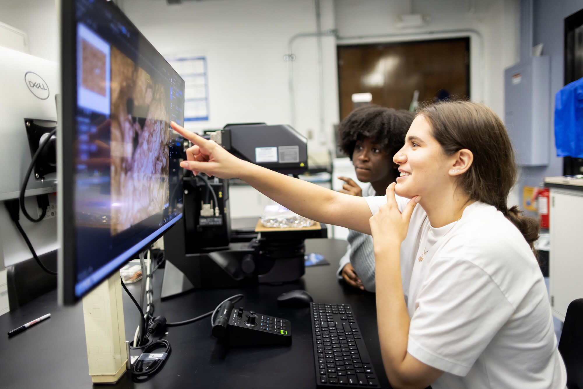 Nafisa Bangura (left) and Angelica Dadda (right) using a computer in the Composto Lab to analyze data and note observations.