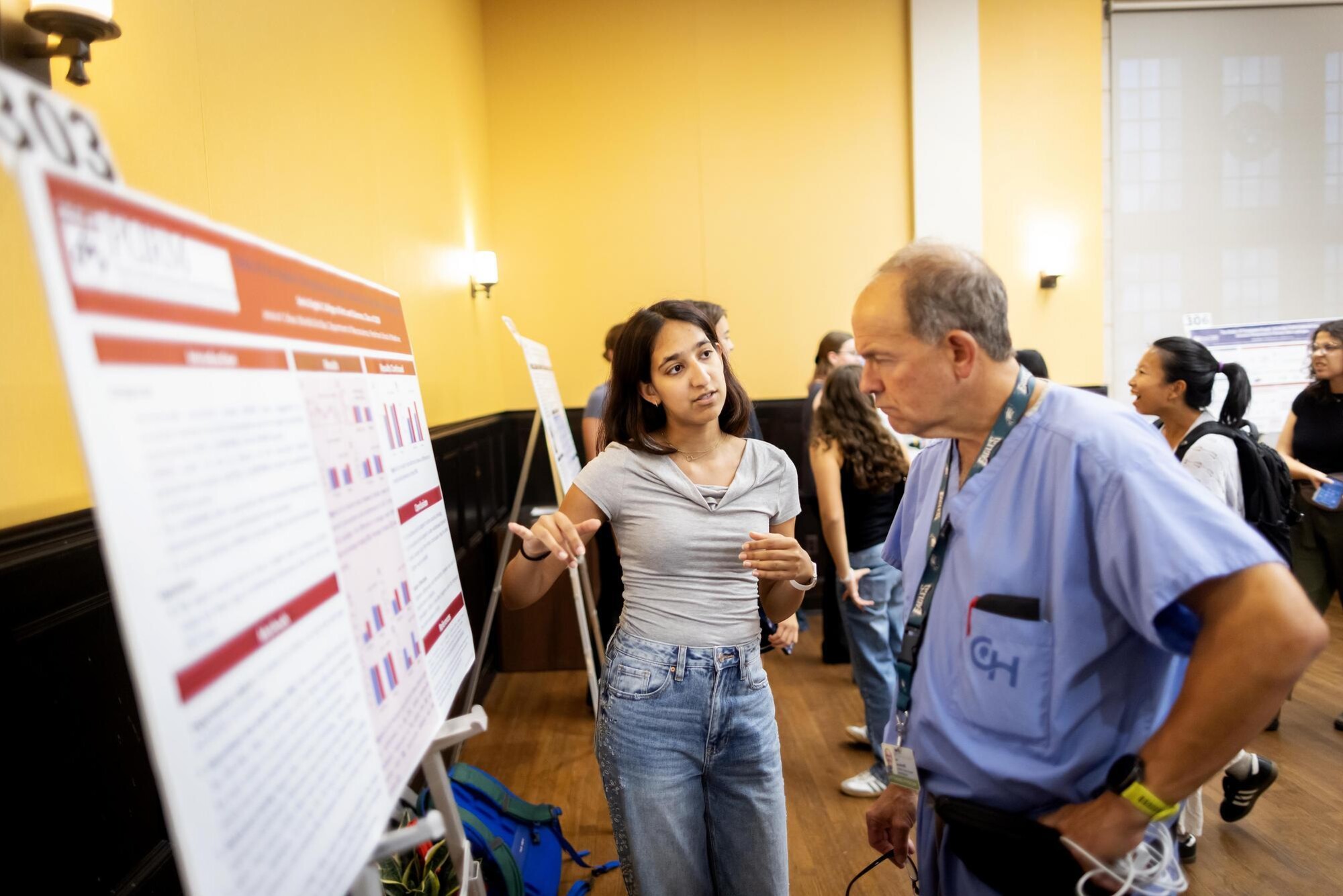 A student shows their poster to a CHOP doctor at the CURF Poster Expo in Houston Hall.