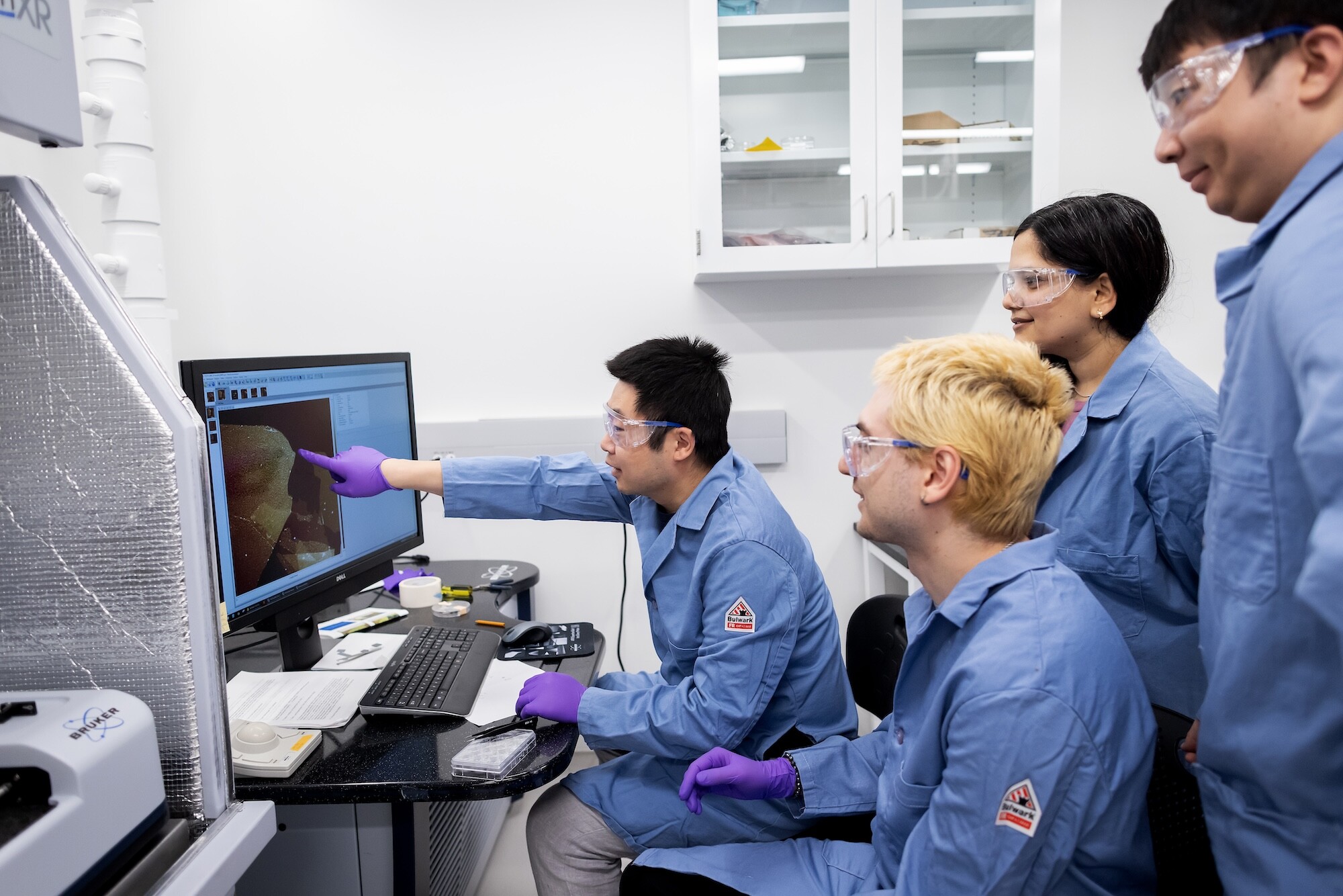 Researchers gather around a screen providing data.