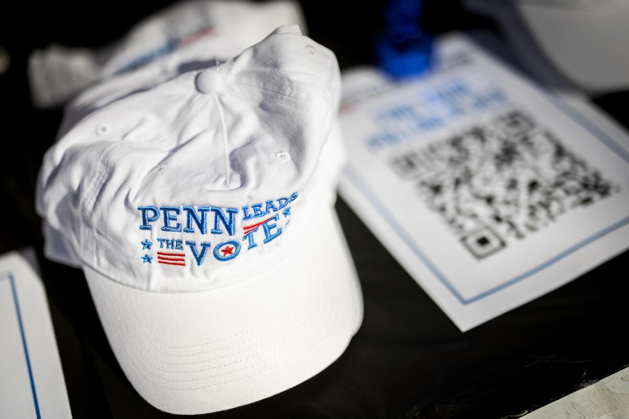 A Penn Leads the Vote hat next to a paper with a QR code