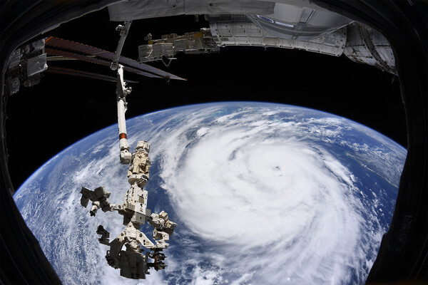View of Hurricane Ida from space with satellite visible above orbit.