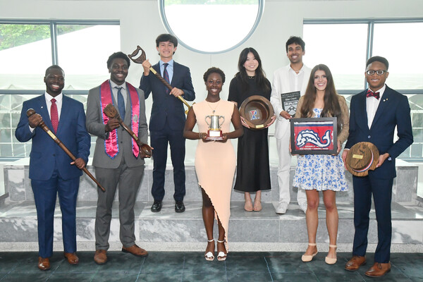 Eight fourth-year students stand with various awards (spoon, shovel, hat, etc)