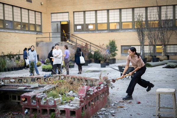 A person with a sledgehammer working on the Breathing Room courtyard.
