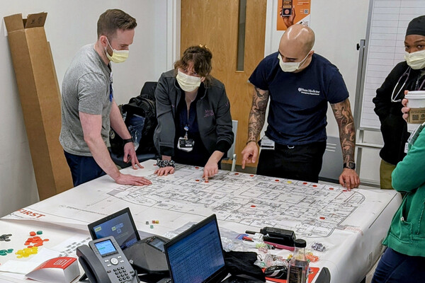 A group of Penn Medicine emergency responders with face masks look over plans during an emergency drill.