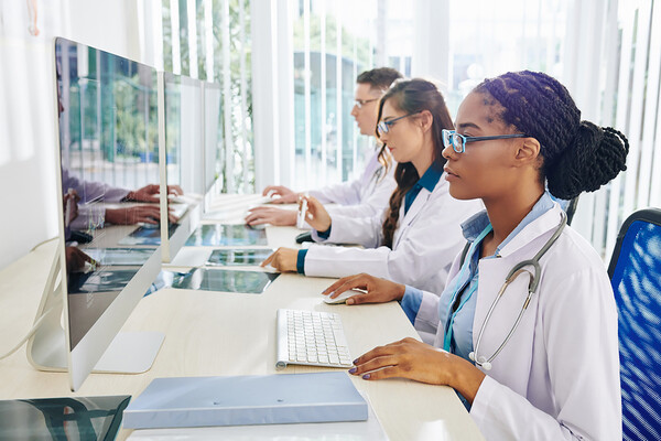 Medical students sit at a long desk in front of computers.