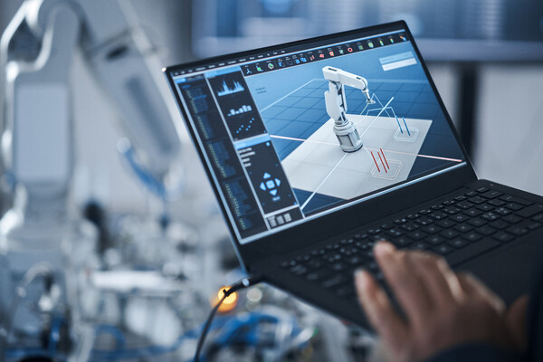 A person programming a robotic arm with a laptop.