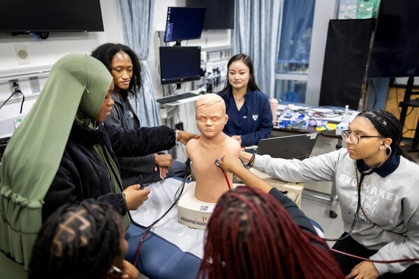 High school students listen to breathing sounds on mannequin.