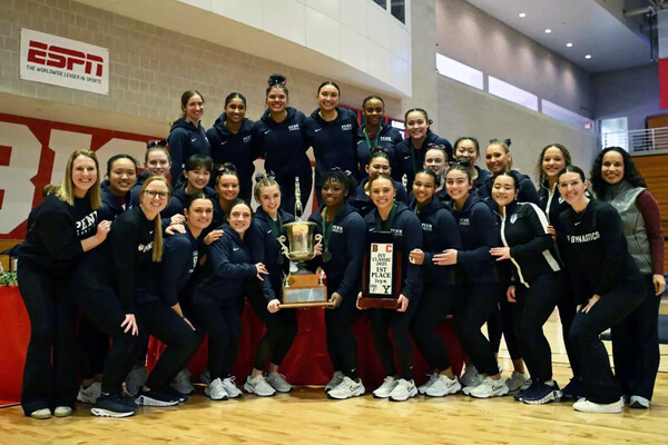 Penn’s gymnastics team holding a trophy.