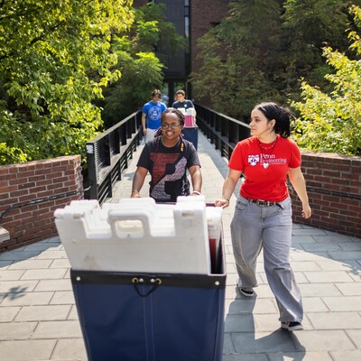 Nilla Orina pushes a Move-In cart with other Move-In coordinators on Penn’s campus.