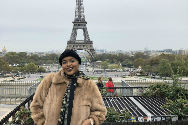 Eva Maria Lewis stands in front of the Eiffel Tower in Paris