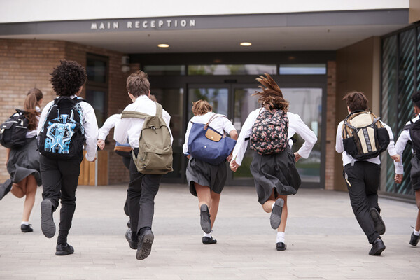 six kids in private school uniforms and backpacks running into school