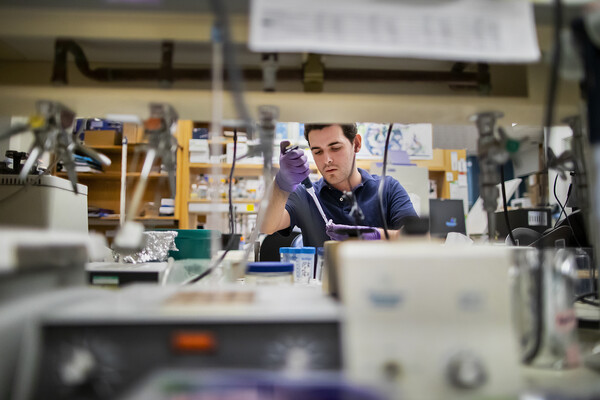 Penn senior Andrew Ravaschiere seated in a laboratory doing a procedure with a syringe