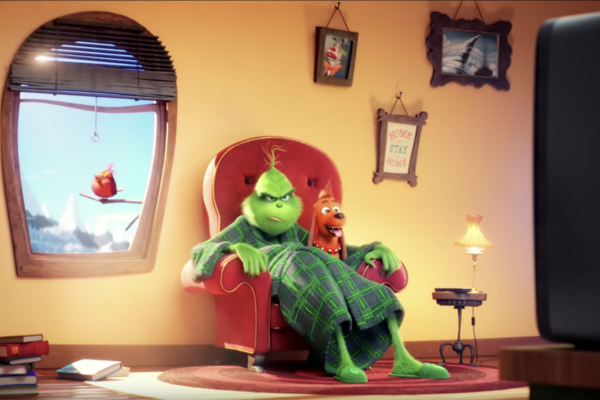 The Grinch lounges on a chair looking grouchy