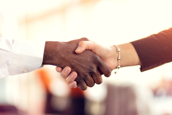 A black man and a white woman shaking hands