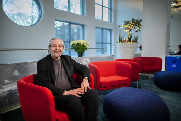 Delli Carpini sits on bright red chair in Annenberg School lobby