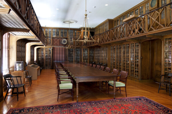 Library room at the Pennsylvania Hospital with a long table, ornate rug and glass cabinets of books
